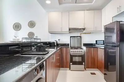a large kitchen with wooden cabinets and stainless steel appliances at Studio in Reef Residence JVC by PK Holidays in Dubai