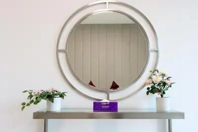 a round mirror on a table with two plants at Livbnb Suites - Lavish 2BR w/ Burj Khalifa Views & Near Dubai Mall in Dubai