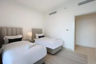two beds in a room with white walls at Livbnb Suites - Lavish 2BR w/ Burj Khalifa Views & Near Dubai Mall in Dubai