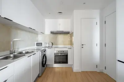 a white kitchen with a sink and a dishwasher at GuestReady - Seaview residence in Dubai Marina in Dubai