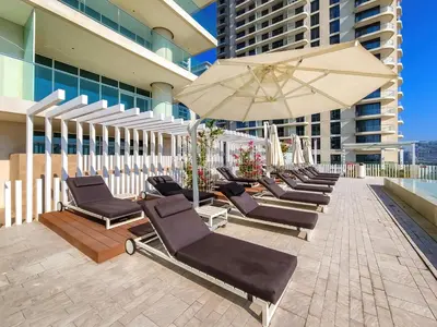 a row of lounge chairs and an umbrella on a rooftop at Emaar Beachfront Sunrise Bay 2bdr apartment in Dubai