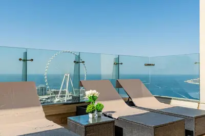 a balcony with chairs and a ferris wheel in the background at Huge Penthouse with yacht included and private pool!!! in Dubai