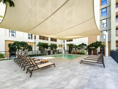 a patio with chairs and a pool in a building at Nice 1BD Apartment in Surf at Creek Beach in Dubai