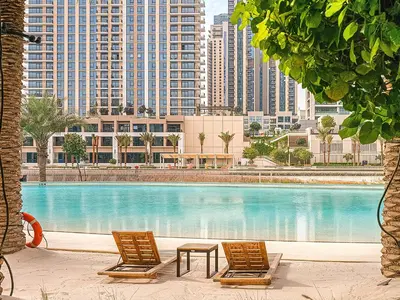 two chairs and a table in front of a large pool at Nice 1BD Apartment in Surf at Creek Beach in Dubai