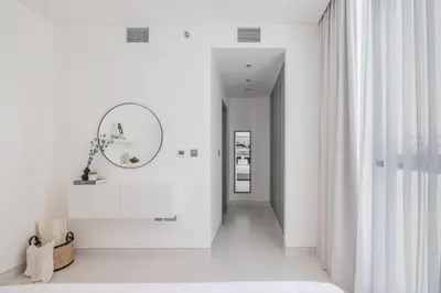 a hallway with white walls and a mirror and a mirror at HiGuests - Step Into Heaven In This Lakeside Apartment in Dubai