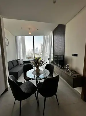 a living room with a table and chairs and a couch at Prime 1BR in Sobha Hartland, Burj Khalifa view in Dubai