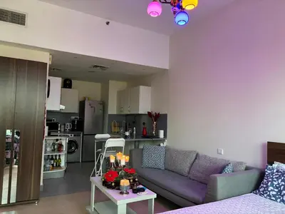 a living room with a purple couch and a kitchen at Studio Apartment - Cozy, Very Accessible and so near to Train Station in Dubai
