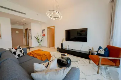 a living room with a couch and a tv at Lux Golf Views 3 BR in Emirates Hills in Dubai