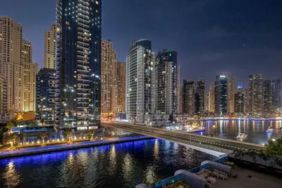 a city at night with a river and buildings at Luxury 2 Bedroom Apartment in Dubai Marina & JBR Beach in Dubai