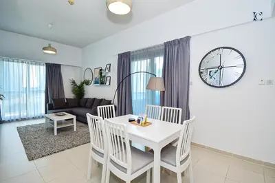a living room with a white table and chairs and a clock at Luxury Escapes - Stylish 1BR Apartment - Close to Metro in Dubai Marina - Cascade Tower in Dubai