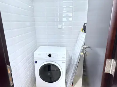 a small bathroom with a washing machine in it at Deluxe Apartment With Panoramic View Near Metro in Dubai