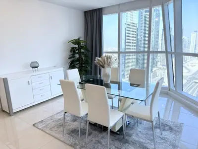 a dining room with a glass table and white chairs at Deluxe Apartment With Panoramic View Near Metro in Dubai