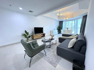 a living room with a couch and a tv at Deluxe Apartment With Panoramic View Near Metro in Dubai