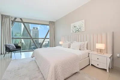 a white bedroom with a bed and a large window at Difc 1 Bd apartment in Park Tower in Dubai