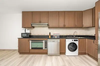 a kitchen with wooden cabinets and a washer and dryer at Lux BnB Princess Tower Palm Ocean Views in Dubai