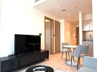 a living room with a tv and a table and chairs at Stylish brand new 1 bedroom in Dubai
