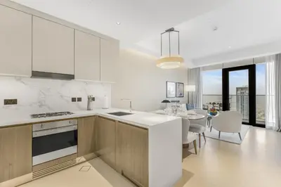 a white kitchen with a table and a dining room at EDEN'S Homes & Villas - Address Opera District Residences in Dubai