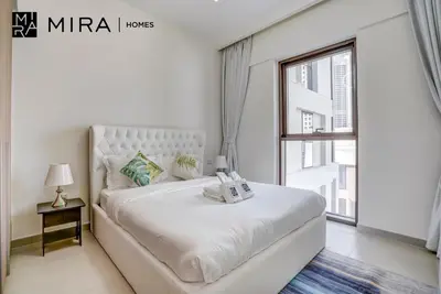 a white bedroom with a large bed and a window at Mira Holiday Homes - Fully furnished 1 bedroom in Creek Harbour in Dubai