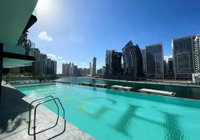 a large swimming pool with a city skyline in the background at Lux Studio in Business Bay -10 mins to Burj Khalifa - Binghatti Canal in Dubai