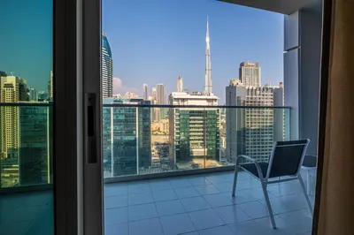 a chair on a balcony with a view of the city at Stylish high floor apartment with Burj View in Dubai