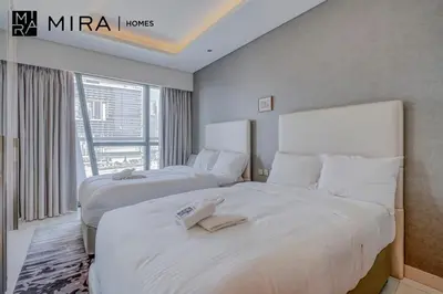 two beds in a hotel room with a window at Mira Holiday Homes - Furnished 1 bedroom in Paramount Tower B in Dubai
