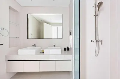 a white bathroom with a sink and a mirror at Silkhaus The Marina View 2BDR Dubai Harbour in Dubai