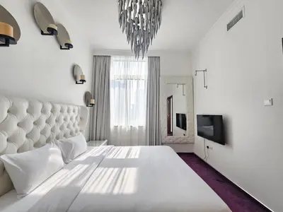 a white bedroom with a large bed and a chandelier at Nice view apartment in Botanica Tower Dubai Marina in Dubai
