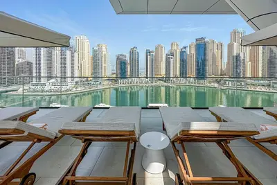 a patio with tables and chairs and a view of a city at NEW Luxe 3BR in Vida Marina w/ Breathtaking Views in Dubai