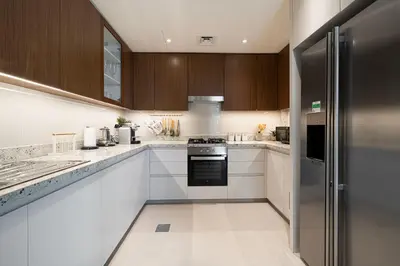a kitchen with white cabinets and a black refrigerator at Magnificent Cozy 2BR in Downtown Dubai in Dubai