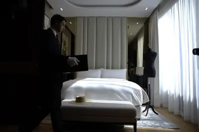 a man in a suit standing in front of a bed at The Biltmore Hotel Villas, Dubai in Dubai