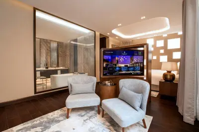 a living room with two chairs and a television at The Biltmore Hotel Villas, Dubai in Dubai