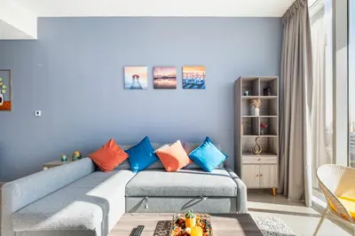 a living room with a blue couch with colorful pillows at Dubai Dreamland 1BR for 4, King Bed, Pool, Sauna, Gym, Free Parking in Dubai
