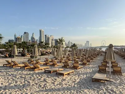 a row of lounge chairs and umbrellas on a beach at Modern Fully-Equipped Apartment in Seven Palm, Beach and Pool Access in Dubai