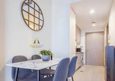 a dining room with a white table and blue chairs at Azizi Riviera 7 - Meydan City, Dubai in Dubai