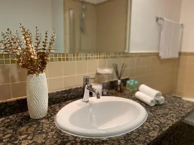 a bathroom counter with a sink and a vase with flowers at JBR Beach Full Sea View 2 BR High Floor in Dubai