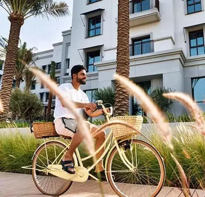 a man riding a bike down a sidewalk at Luxury 1BR Retreat @ Vida Residences - Creek Beach in Dubai