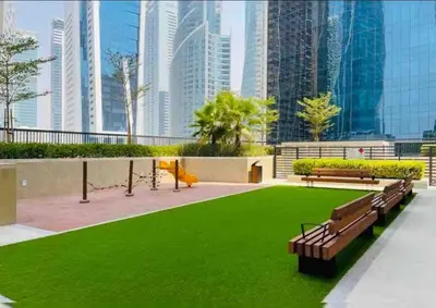 a park with benches and green grass and buildings at Near Burj Khalifa NYE Brand New Cozy 1BR Business Bay in Dubai