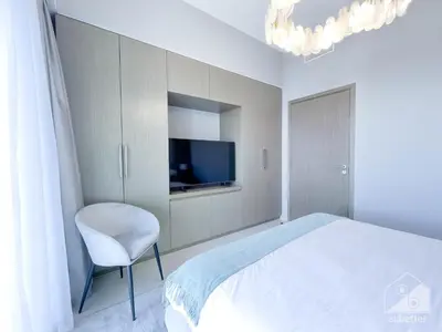 a bedroom with a bed and a chair and a tv at Luxury Burj Royale Apt balcony & Breathtaking View in Dubai
