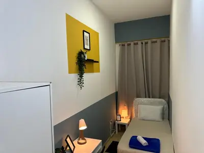 a small bedroom with a bed and a chair at Spacious Mini Partition Room Near Emirates Mall in Dubai