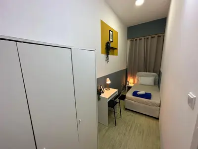 a small bedroom with a bed and a desk at Spacious Mini Partition Room Near Emirates Mall in Dubai