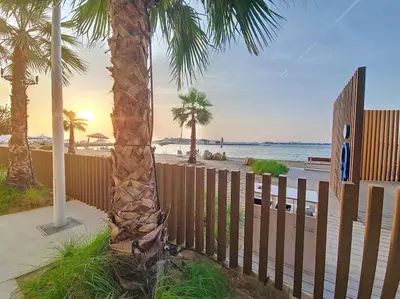 a palm tree next to a fence on the beach at Beach Isle - Gorgeous One Bedroom in Dubai