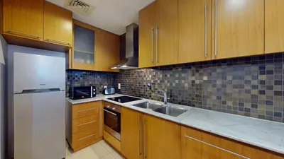 a kitchen with wooden cabinets and a white refrigerator at Iris Blue - Neat One Bedroom in Dubai