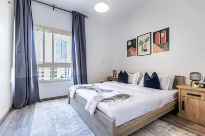 a bedroom with a large bed and a large window at Serene & Spacious 1BR The Greens in Dubai