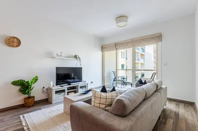 a living room with a couch and a tv at Serene & Spacious 1BR The Greens in Dubai