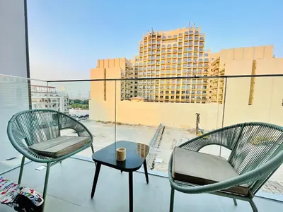 two chairs and a table on a balcony with a building at Luxury 1 Bedroom Apartment in Dubai