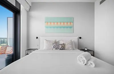 a white bedroom with a large white bed with pillows at Palm View - Beach Vista T1 in Dubai