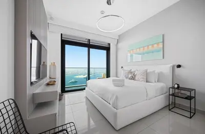 a white bedroom with a large bed and a large window at Palm View - Beach Vista T1 in Dubai