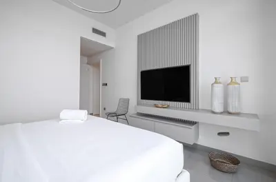 a white bedroom with a bed and a tv at Palm View - Beach Vista T1 in Dubai