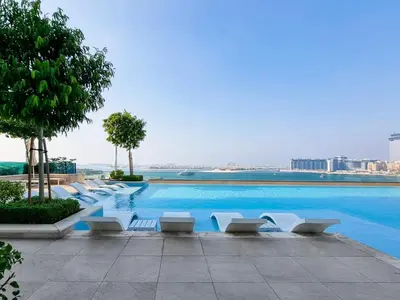 a large swimming pool with white lounge chairs in a building at Palm View - Beach Vista T1 in Dubai