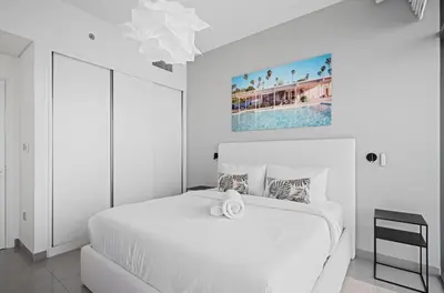 a white bedroom with a white bed and a painting at Palm View - Beach Vista T1 in Dubai